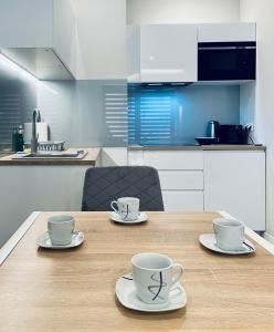 einem Holztisch mit zwei Kaffeetassen darüber in der Unterkunft Modern Silver Apartment in Krakau