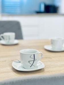 eine Kaffeetasse auf einem Teller auf einem Tisch in der Unterkunft Modern Silver Apartment in Krakau