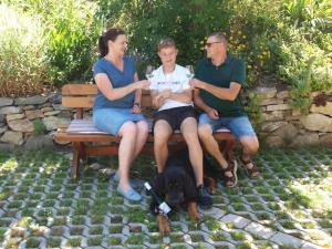 a group of three people sitting on a bench with a dog at Weinbau Weidenauer in Wösendorf