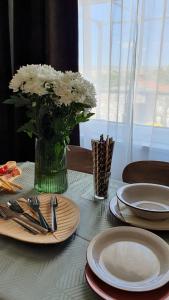 una mesa con platos y un jarrón de flores blancas en Apartmani Masline en Jasenice