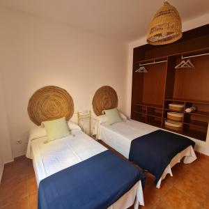 sypialnia z dwoma łóżkami i koszami na ścianie w obiekcie Casa M de mar - Dúplex con vistas w Corralejo