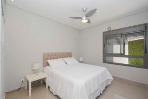 a white bedroom with a bed and a window at Casa com piscina perto da praia de Riviera in Riviera de São Lourenço +46 photos