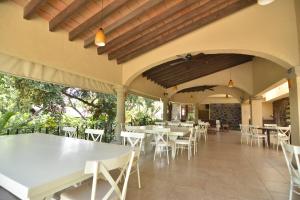 a restaurant with white tables and white chairs at Hotel Coral Cuernavaca in Temixco