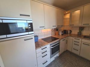 a kitchen with white cabinets and a microwave at Stylische Wohnung mit Weitblick und großem Balkon in Karolinenkoog
