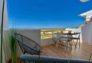 een balkon met een tafel en stoelen en uitzicht op de oceaan bij Apartamento Aldeia de Marim, Ohao, Portugal, Meerblick in Olhão