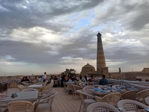 a group of people sitting at tables with a lighthouse in the background at Minor Boutique Hotel in Khiva