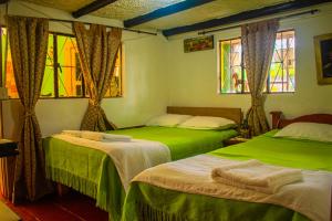 2 camas verdes en una habitación con ventanas en Miramonte Hostal, en Paipa