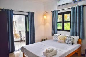 1 dormitorio con 1 cama con cortinas azules y ventana en SOLS Backyard, en Arambol
