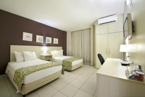 a hotel room with two beds and a desk at Nobile Inn Executive Ribeirao Preto in Ribeirão Preto