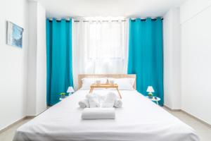 a bedroom with a large white bed with blue curtains at Brand New Studio near Downtown in Heraklio