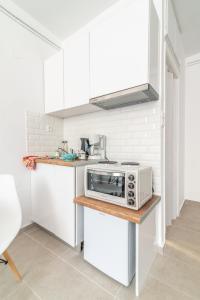 a kitchen with white cabinets and a microwave on a counter at Brand New Studio near Downtown in Heraklio