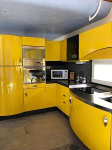 a yellow kitchen with yellow cabinets and a sink at BluVilla in Malvaglia