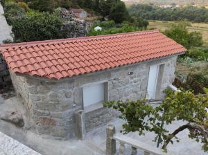 una pequeña casa de piedra con techo rojo en Casa do Vale - Casa Termal - Gerês/Xures, en Lobios