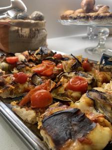 a pizza with tomatoes and mushrooms on a tray at MAR60 Apartments in Caorle