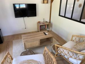 ein Wohnzimmer mit einem TV und einem Tisch in der Unterkunft La Maison de Maxou in Montauban