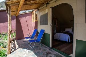 two blue chairs sitting on the porch of a house at Inca Trail Glamping in Cusco