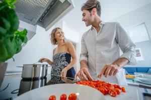a man and woman in the kitchen preparing tomatoes at MAR60 Apartments in Caorle