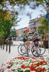 a man and a woman riding bikes down a street at MAR60 Apartments in Caorle