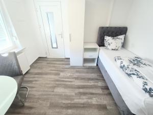 a small white room with a bed and a chair at FMI33 Accommodation Next to Airport in Kelsterbach