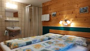 1 dormitorio con 1 cama con pared de madera y lavamanos en Appartment Florian, en Sankt Leonhard im Pitztal