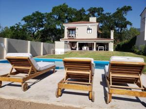 two lounge chairs and a house with a pool at Casa del buen recuerdo San Lorenzo -SALTA- in San Lorenzo