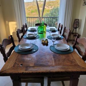 a wooden table with chairs and plates and wine glasses at Villa Farangi in Gállos