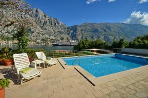 een zwembad met 2 ligstoelen naast het zwembad bij Muo Apartments in Kotor