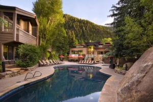 a swimming pool in front of a house at Luxury 1 Bedroom Downtown Aspen Vacation Rental With Access To A Heated Pool, Hot Tubs, Game Room And Spa in Aspen