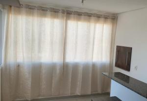 a room with a window with curtains and a television at Novo apto com 100 metros da Av. Brasil in Passo Fundo