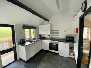 a kitchen with white cabinets and a sink and a toilet at Robyns Nest, self catering cottage in Welshpool
