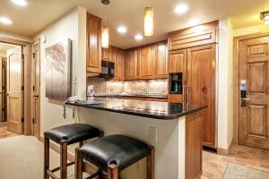 a kitchen with wooden cabinets and a counter with stools at 1 Bedroom In Lionshead Village - Antlers At Vail in Vail