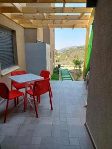 a patio with red chairs and a table with a view at קסם הכפר in Ein Kinya