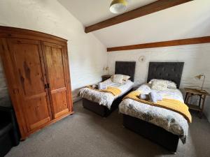 a bedroom with two beds and a wooden cabinet at Cedar Lodge in Looe