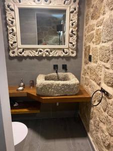 uma casa de banho com um lavatório e um espelho numa parede de pedra em Casa da Avó Maria em Monsanto