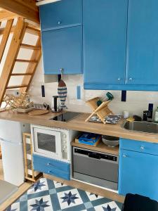 een keuken met blauwe kasten en een magnetron bij Studio Mezzanine La vie en bleu- Vue mer Deauville in Deauville