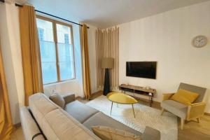 uma sala de estar com um sofá e uma televisão em L'Ilot du Perche: Appartement cosy avec jardin em Bellême