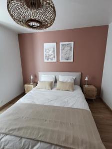 a bedroom with a large bed and a chandelier at L'Ilot du Perche: Appartement cosy avec jardin in Bellême