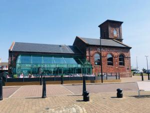 a brick building with a clock tower in front of it at Arran Ferry Apartment in Ardrossan