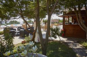 een patio met tafels, stoelen en bomen bij Club Parco Blu in Cala Gonone