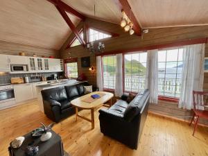 a living room with black leather furniture and a kitchen at Ocean View Panorama in Gravdal