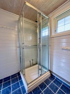 W łazience wyłożonej niebieskimi kafelkami znajduje się przeszklony prysznic. w obiekcie Ocean View Panorama w mieście Gravdal
