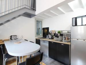 eine Küche mit einem weißen Tisch und schwarzen Schränken in der Unterkunft Bel Appartement T2 Duplex en Hyper Centre, 3*, Parking, 4 Pers., Proche Thermes et Commerces - FR-1-608-233 in La Bourboule + 4 Fotos