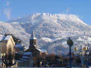 einen schneebedeckten Berg vor einer Stadt mit einer Kirche in der Unterkunft Bel Appartement T2 Duplex en Hyper Centre, 3*, Parking, 4 Pers., Proche Thermes et Commerces - FR-1-608-233 in La Bourboule