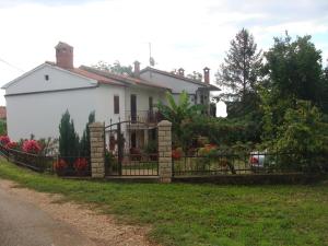 a white house with a gate in front of a yard at Apartment Boris in Labin