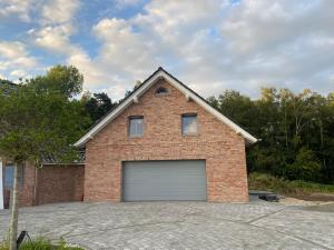 a large brick house with a garage at Ferienwohnung - Flüggenhofsee in Munster im Heidekreis