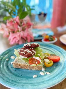 a blue plate with a sandwich and tomatoes on it at Hostal Baruch in Buritaca