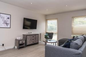 a living room with a couch and a tv on a wall at 3 Bed Private Bungalow Close to Amenities, Wifi, Parking by Ark SA in Sheffield