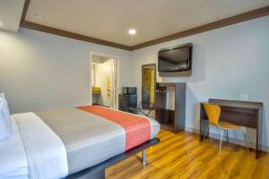 a bedroom with a bed and a desk and a tv at Motel 6 Gardena in Gardena