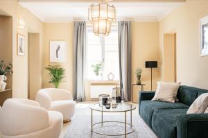 uma sala de estar com um sofá verde e cadeiras brancas em Bogoria Residence - LoftAffair Collection em Cracóvia