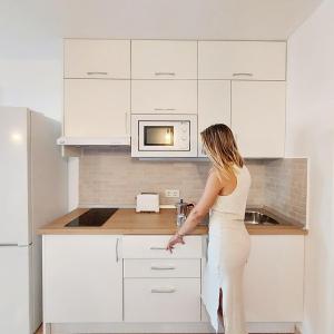 a woman is standing in a white kitchen at Cotillo Ocean in Cotillo